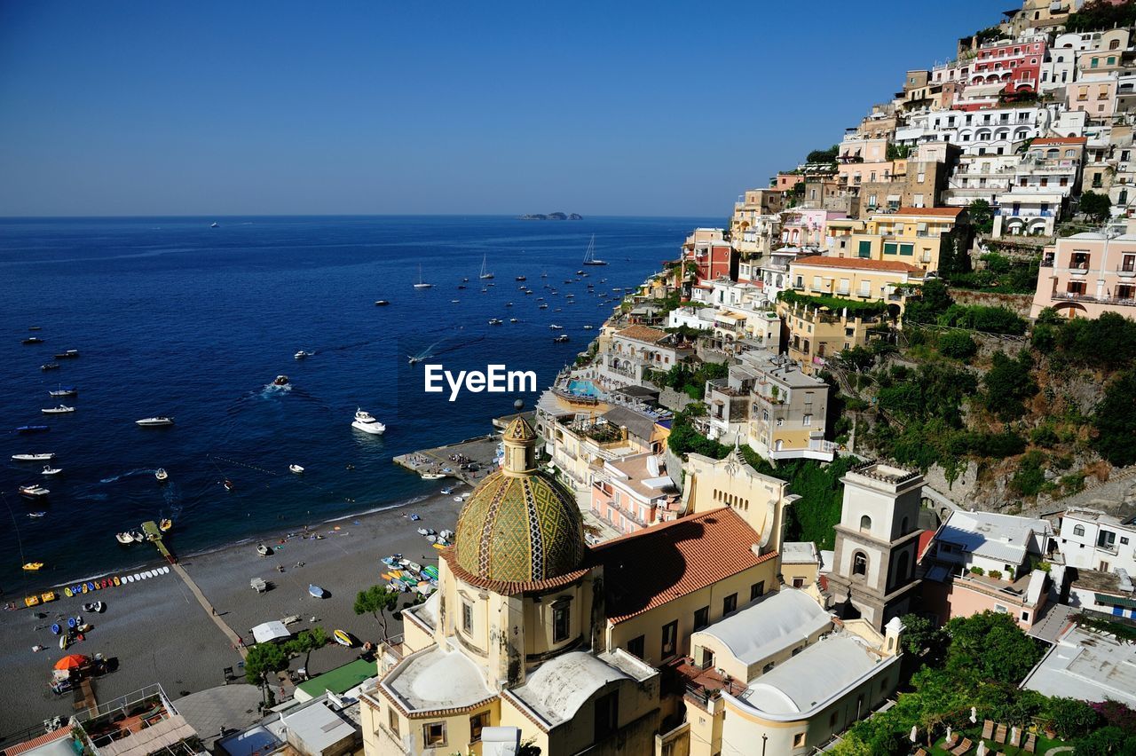 Buildings by sea on cliff against clear sky at positano