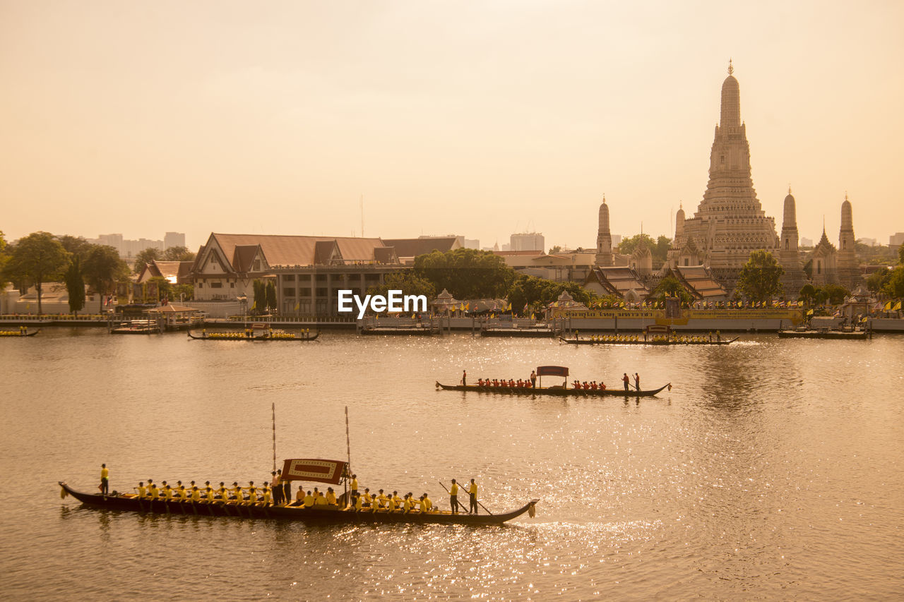 BOATS MOORED IN RIVER AGAINST BUILDINGS