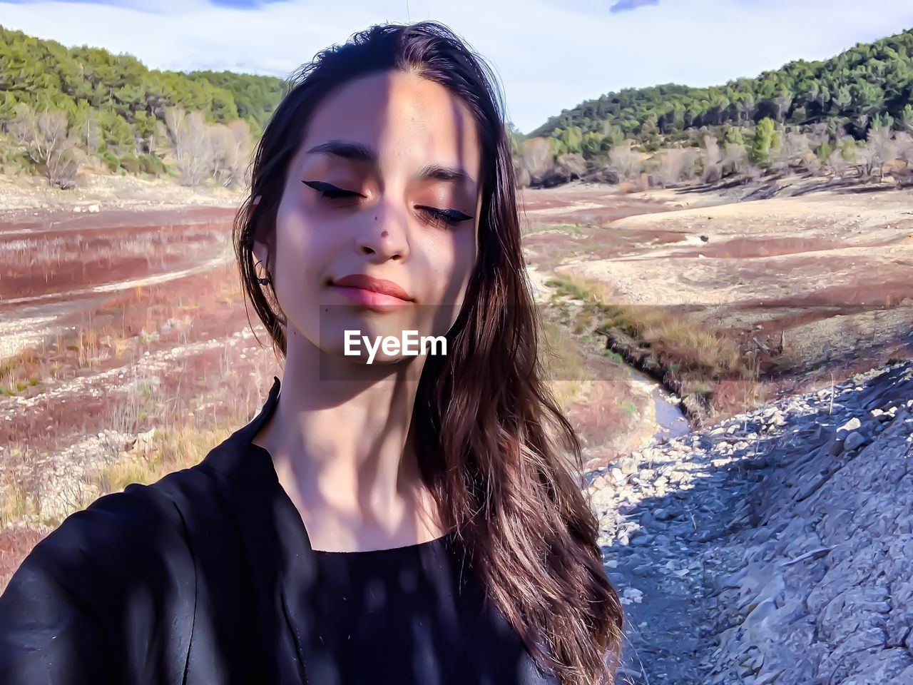 Young woman with closed eyes against landscape