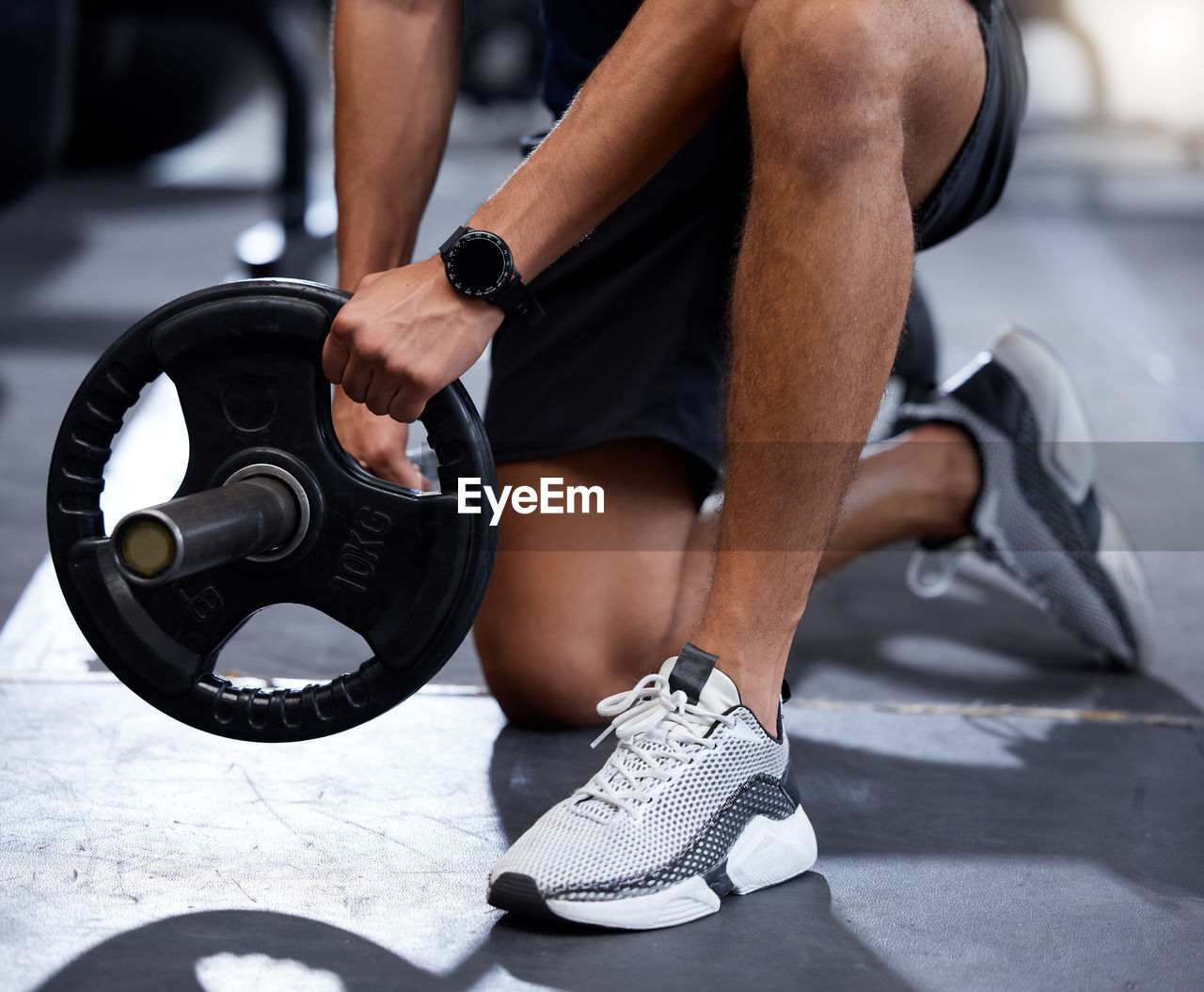 low section of man exercising with dumbbell in gym