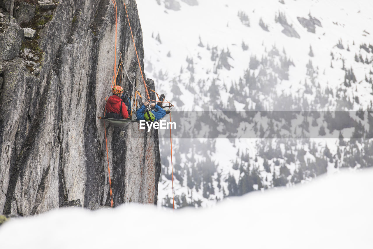 Rock climbers rest on a portaledge during a multi-day climbing trip.