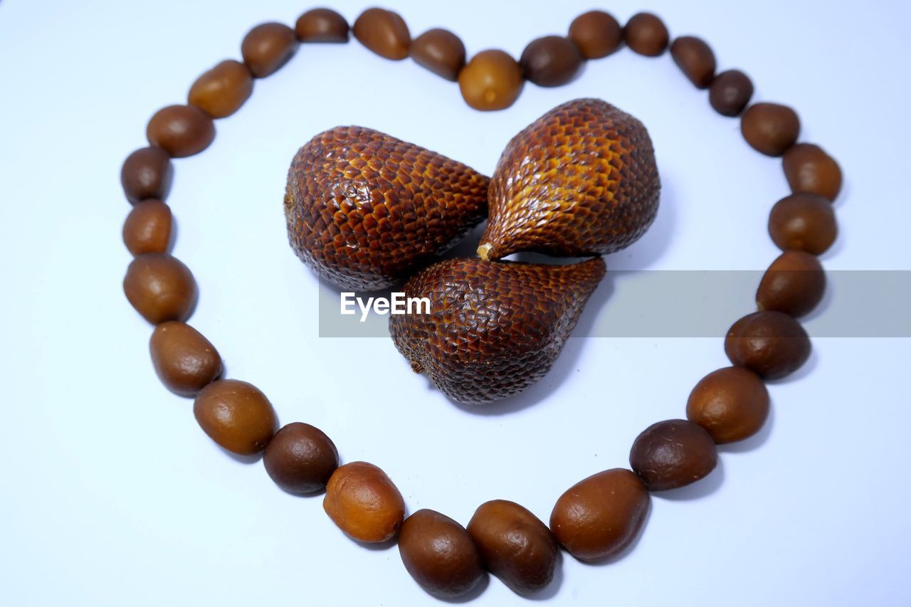 Close-up of heart shape made with snake fruits on white background