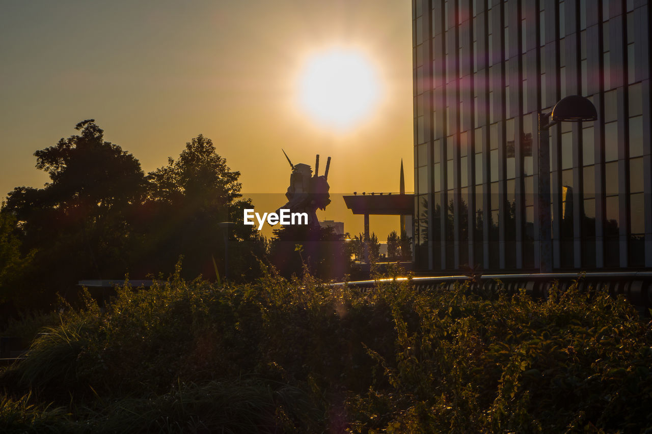 SILHOUETTE OF STATUE IN CITY AT SUNSET