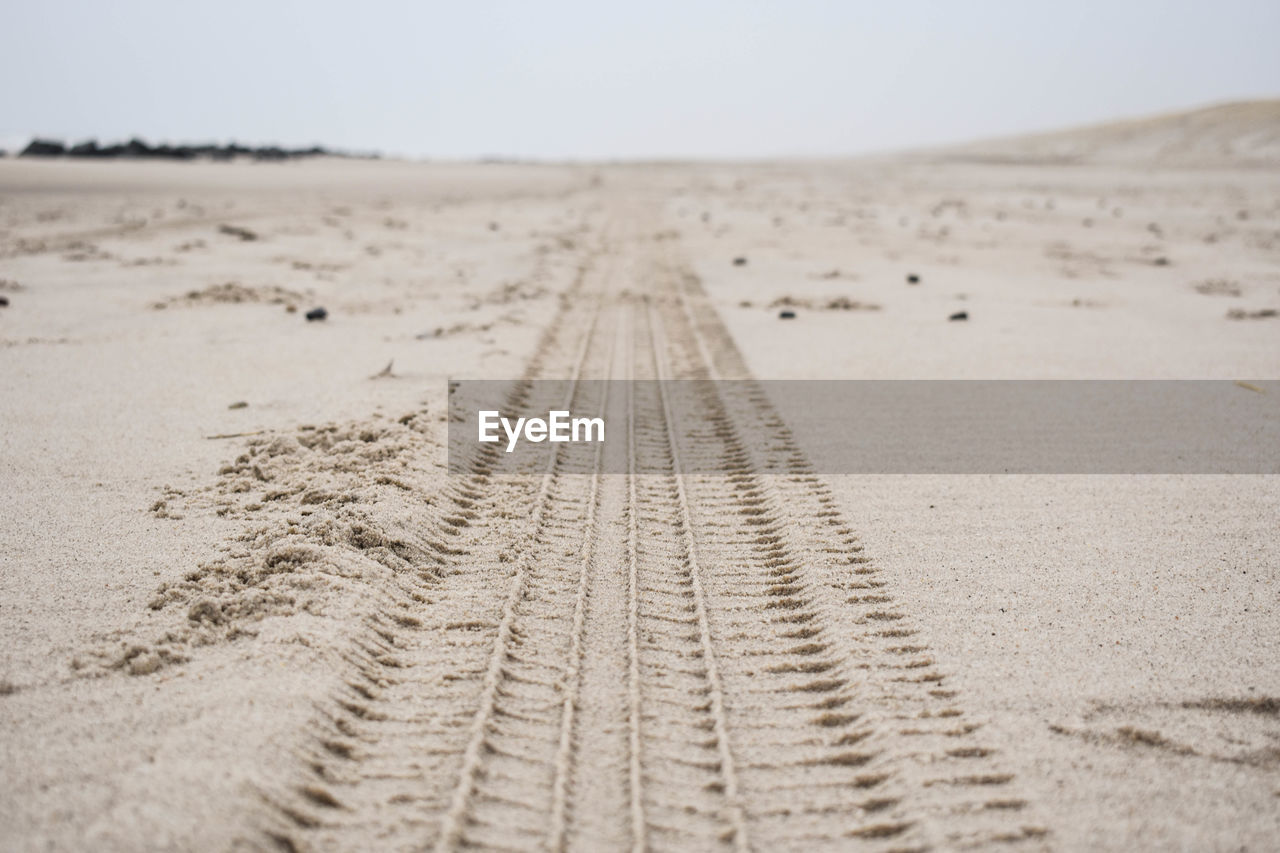 VIEW OF TIRE TRACKS ON SAND DUNE