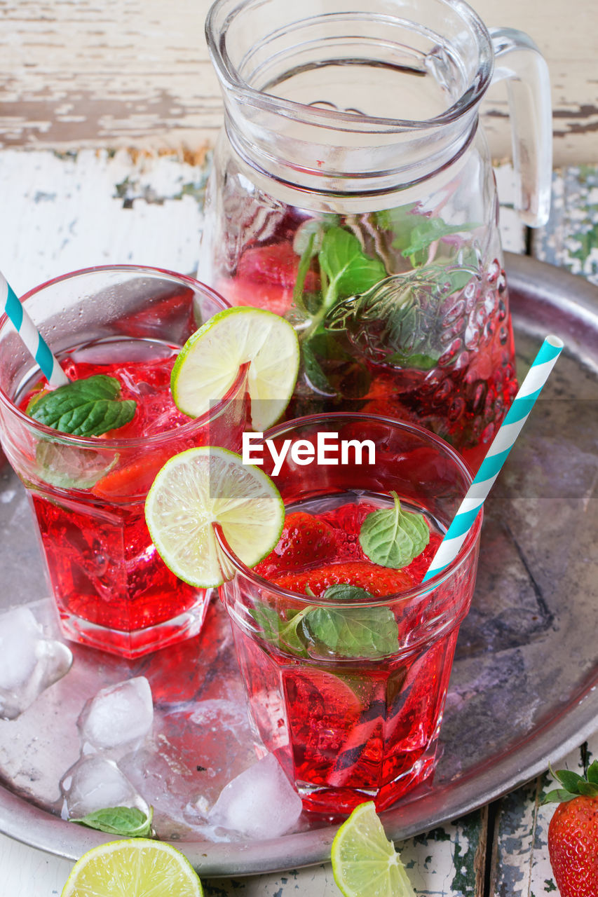 High angle view of cocktail in glasses and jar on wooden table