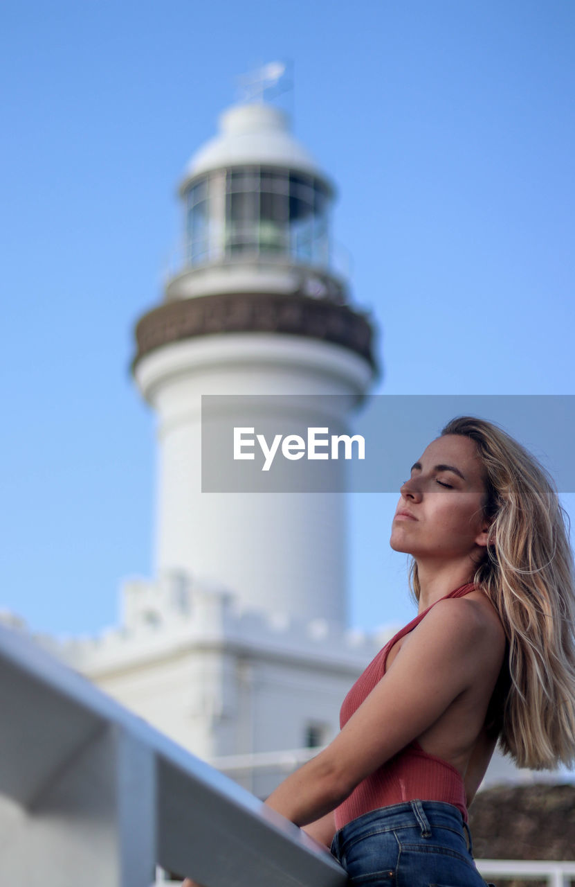 Close up portrait of woman leaning next to the byron bay lighthouse in australia