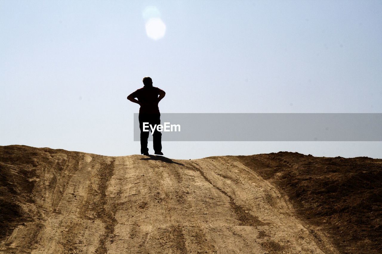 Rear view of man standing on mountain against clear sky