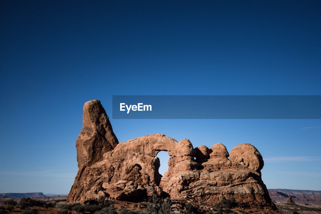 Low angle view of rock formation against clear blue sky