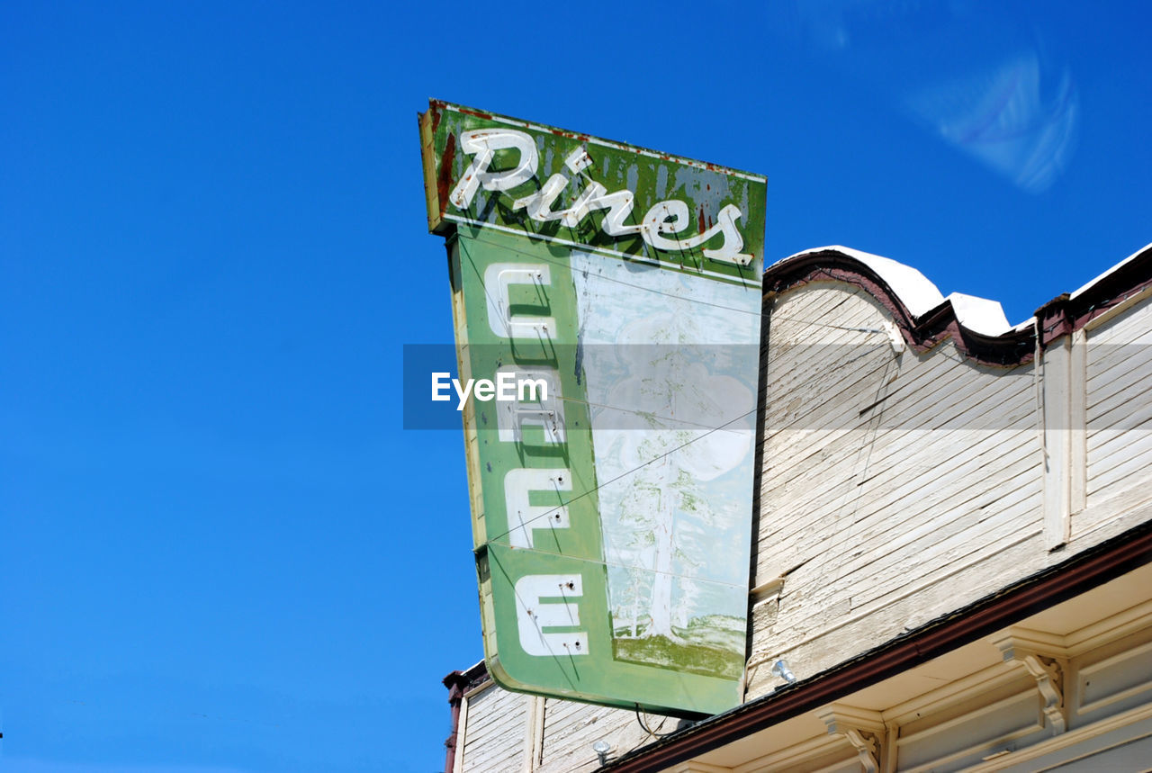 Low angle view of signboard outside cafe against sky