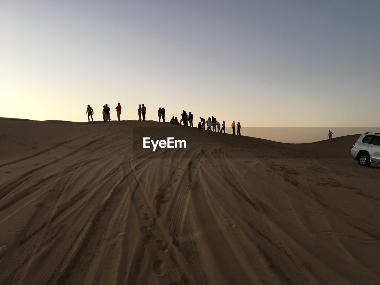 People on desert against sky during sunset