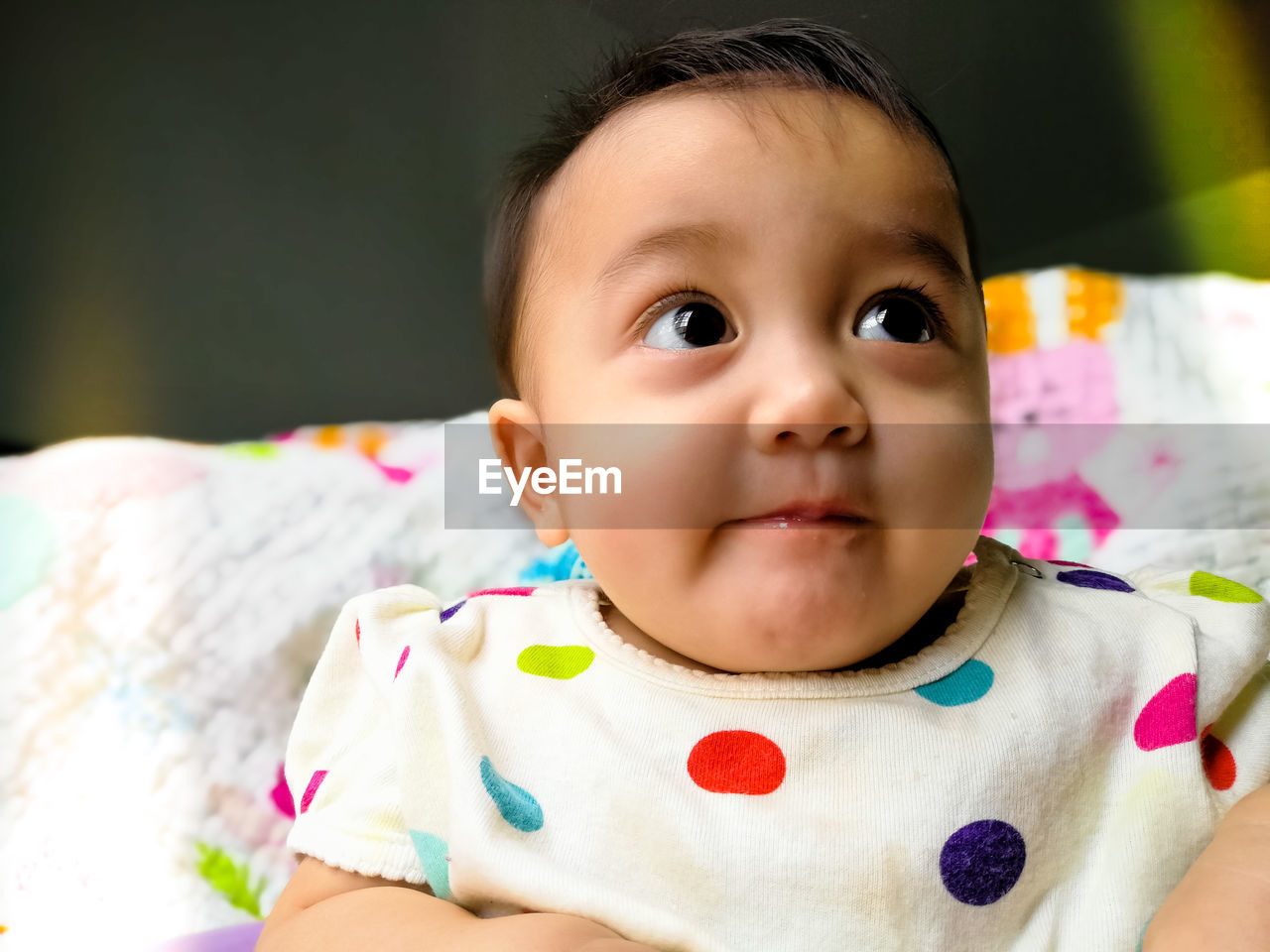 Close-up of cute baby girl on bed at home