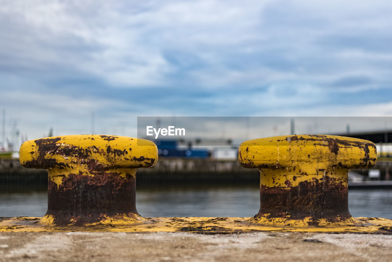 Rusty yellow bollards at harbor