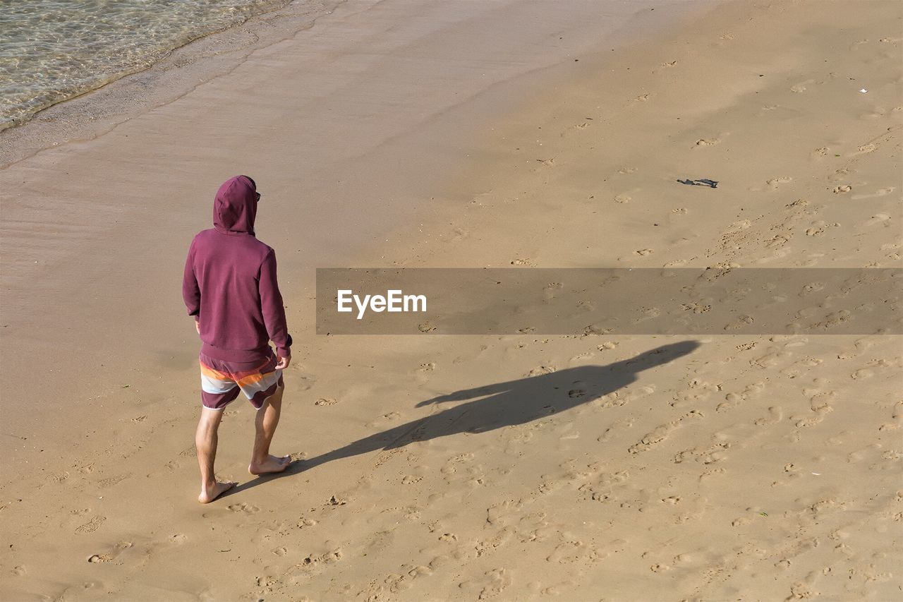 Rear view full length of man walking at sandy beach
