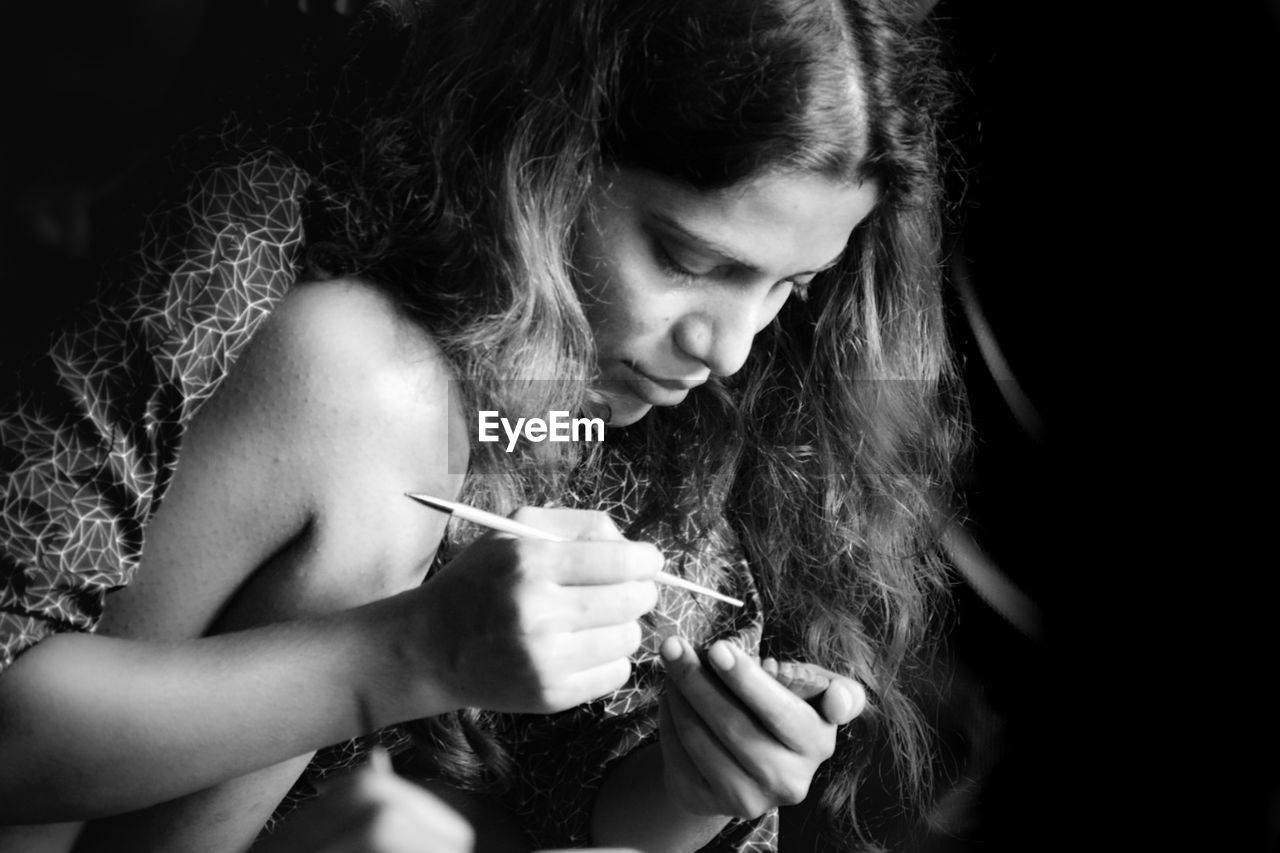 close-up of young woman using mobile phone against black background