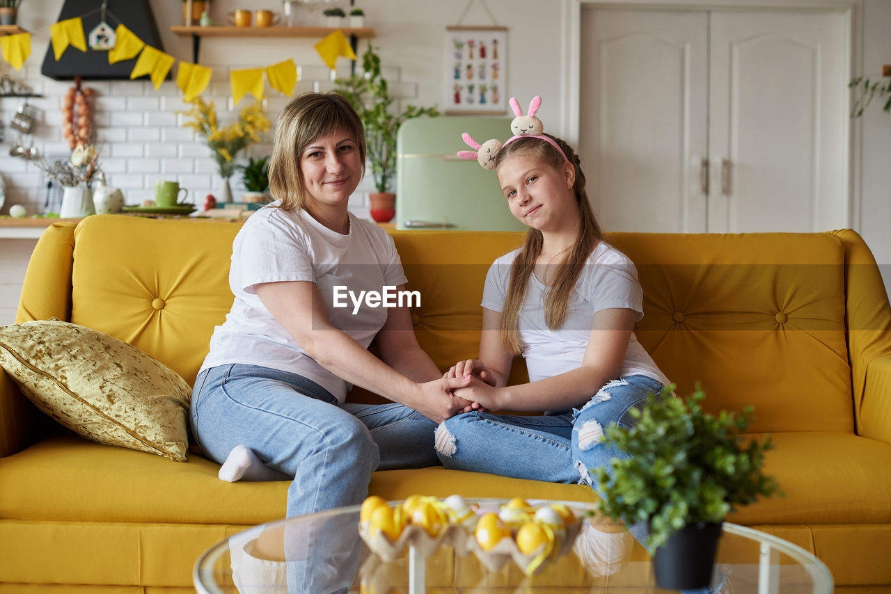 female friends using laptop while sitting on sofa at home