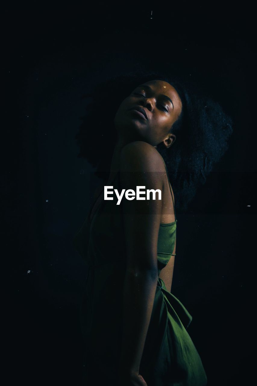 Young woman standing against black background