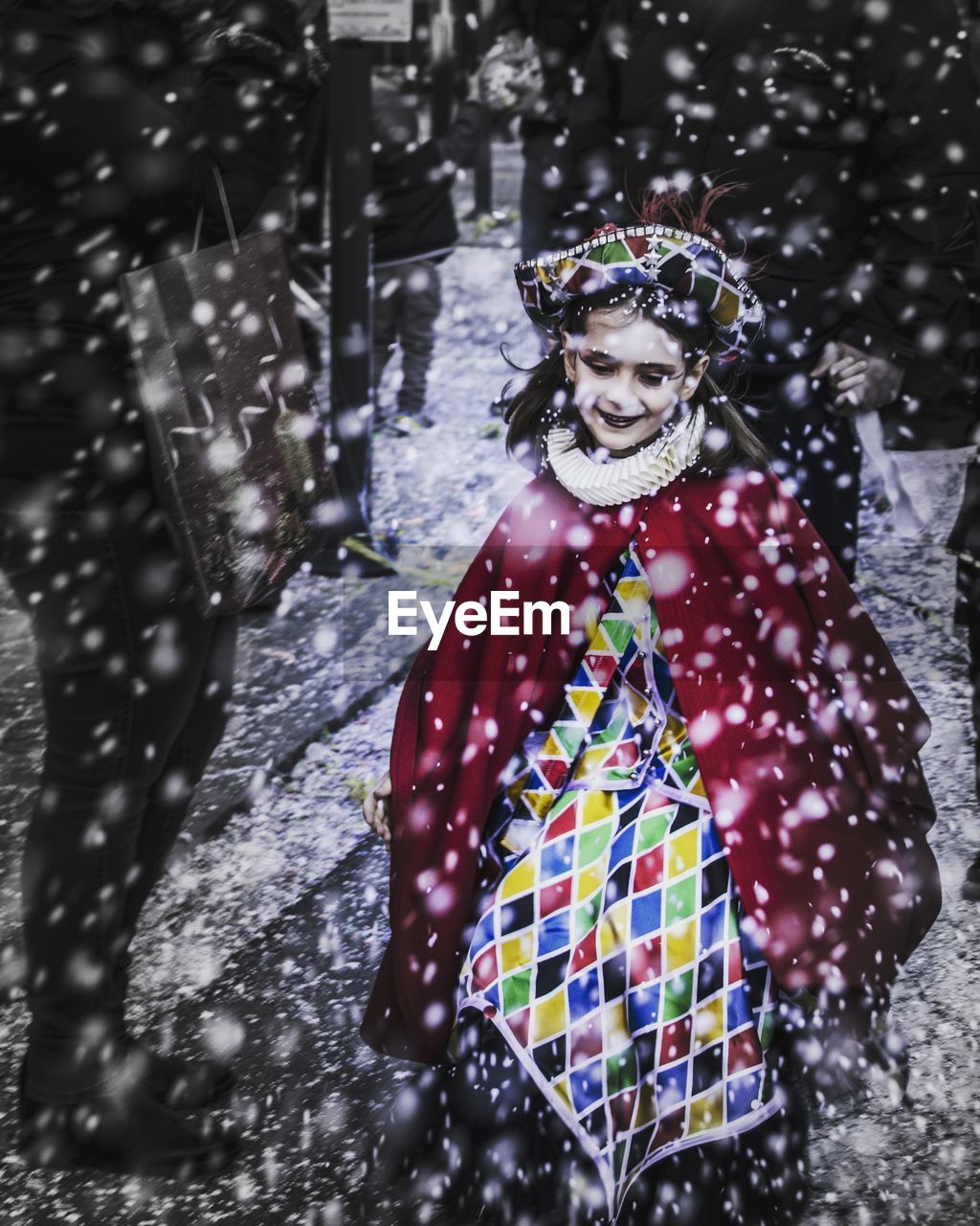 High angle view of smiling girl standing on road during snowfall