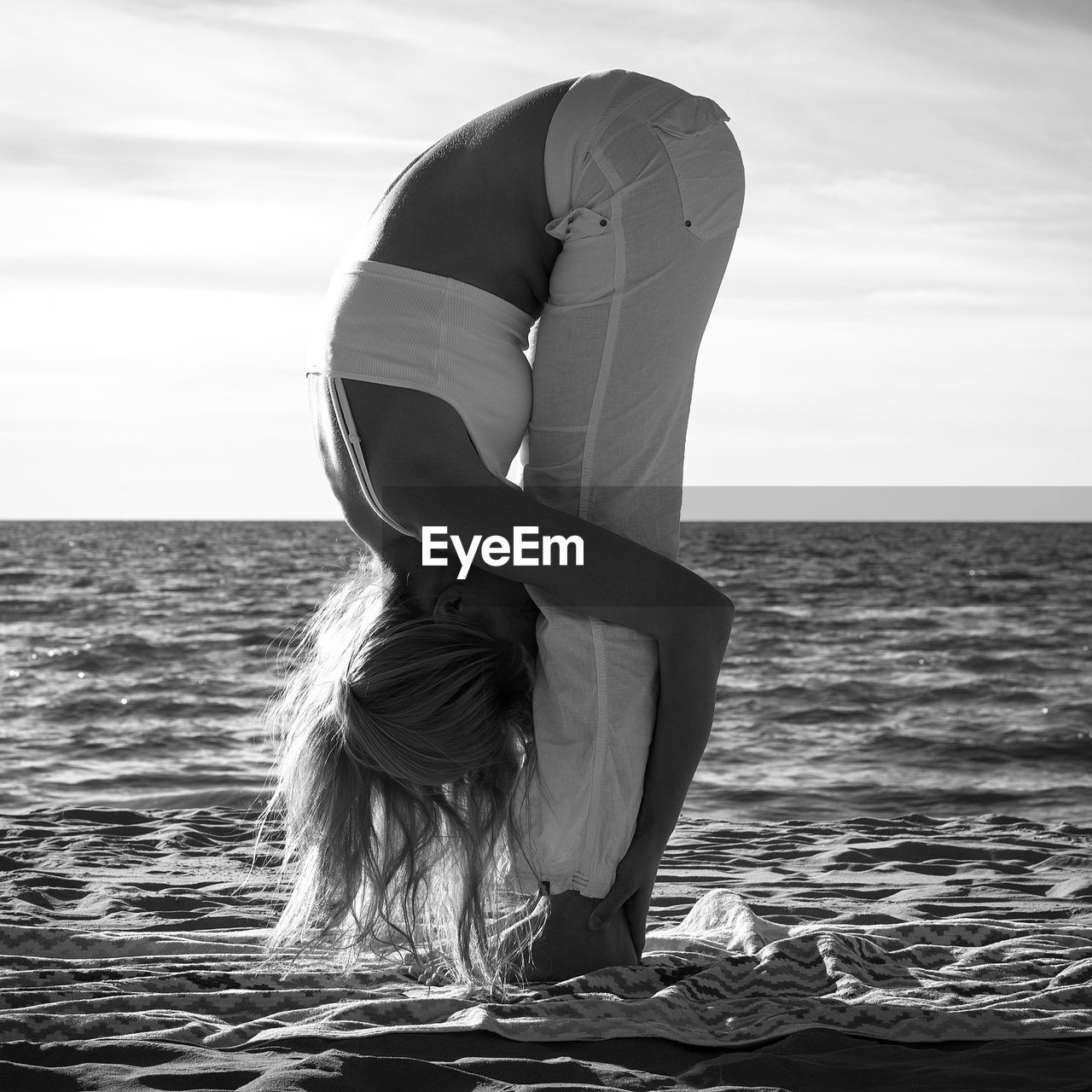 Side view of woman practicing yoga at beach