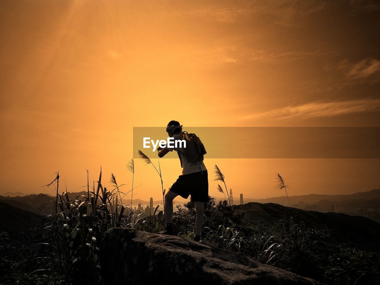 MAN STANDING ON FIELD AGAINST SKY DURING SUNSET