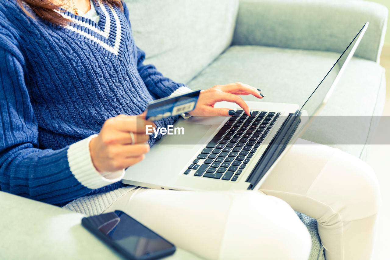 Midsection of woman using laptop for online banking