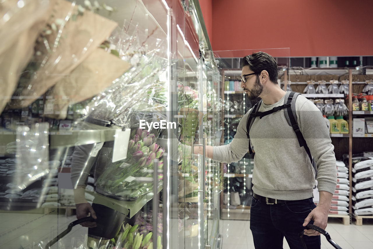 Man standing by flowers on display at supermarket