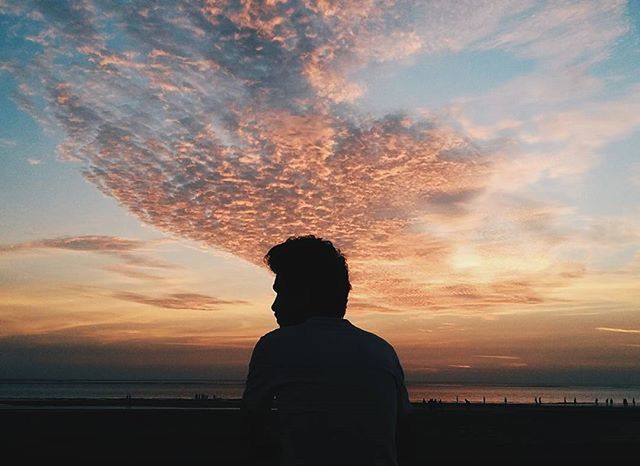 SILHOUETTE OF PEOPLE STANDING ON BEACH AT SUNSET