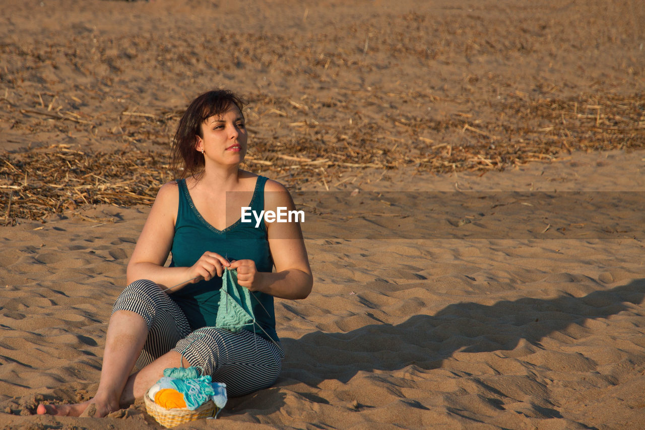 Young woman sitting on sand at beach