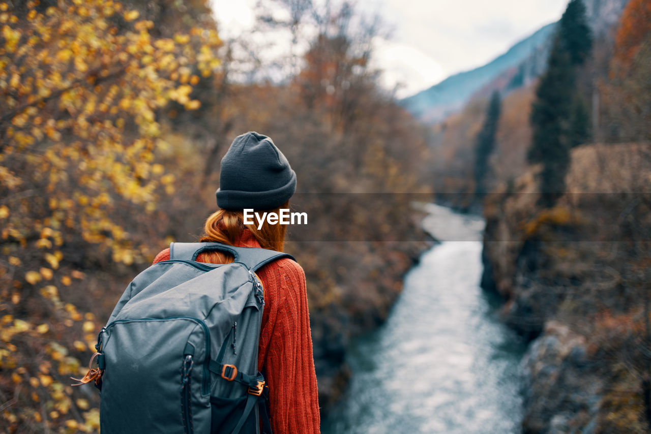 REAR VIEW OF WOMAN STANDING DURING AUTUMN