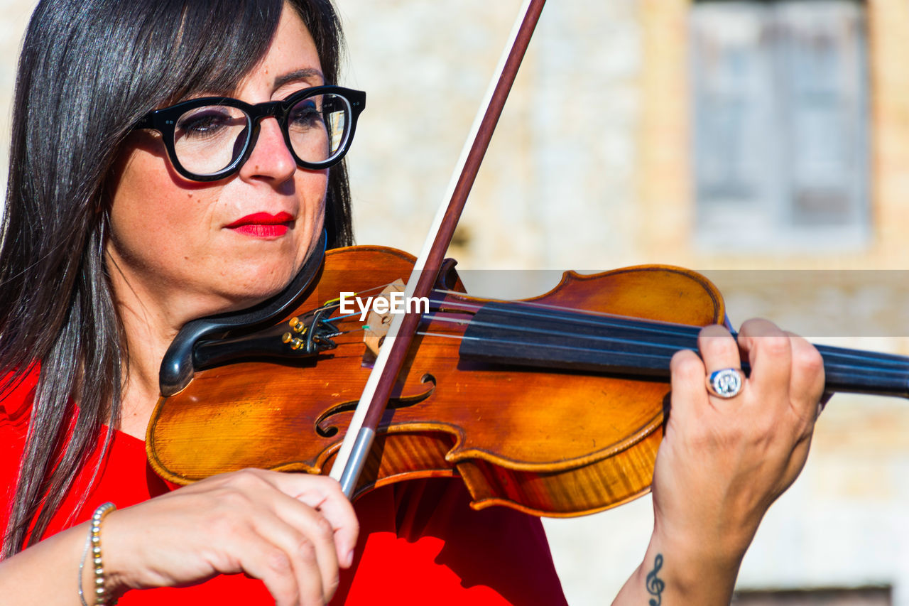 Close-up of woman playing violin in city