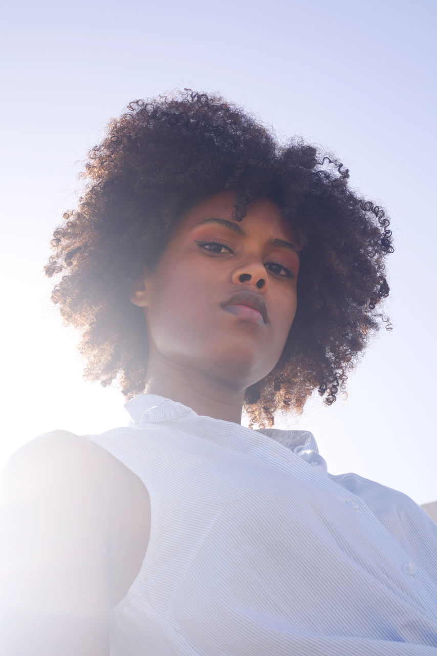 Low angle muted colors portrait of a young black woman with afro hair