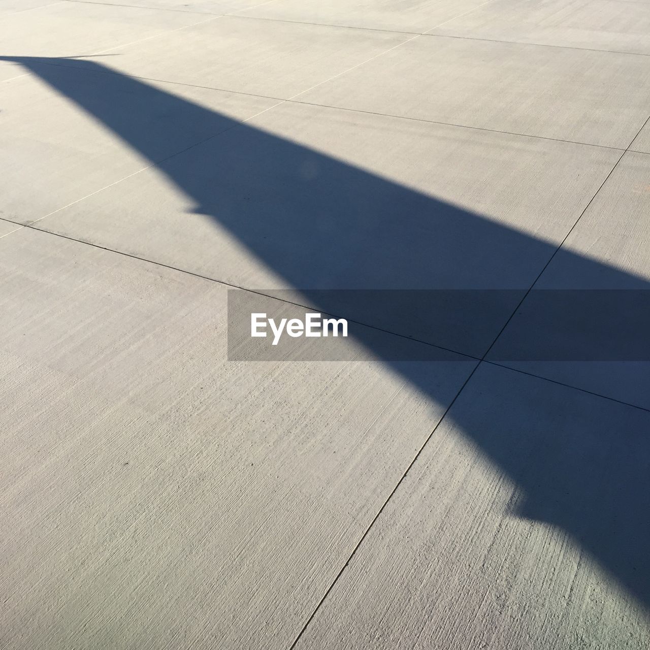 Shadow of aircraft wing on runway during sunny day