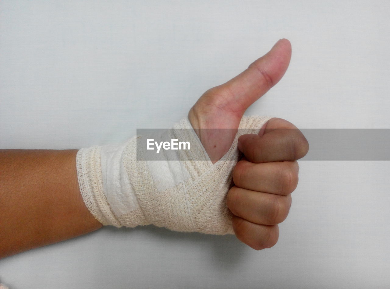 Cropped image of hand with bandage on white background