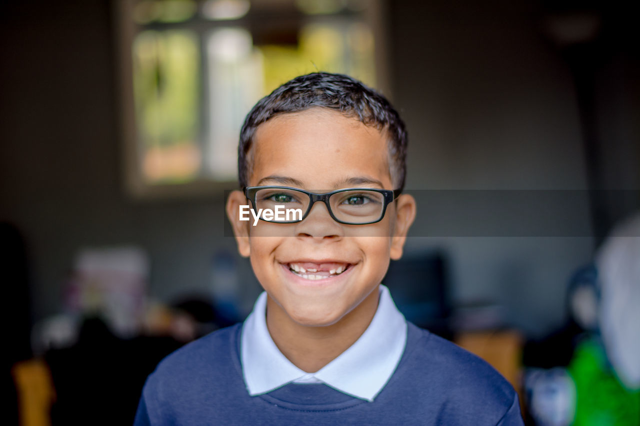Close-up portrait of happy boy wearing eyeglasses while standing at home