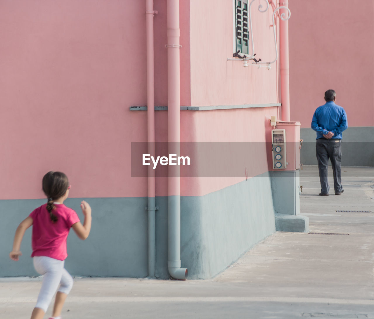 Rear view of daughter running towards father in city