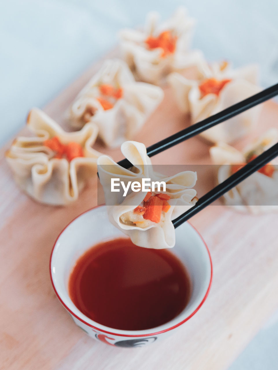 Close-up of chinese dimsum on wood chopper board with hot sauce