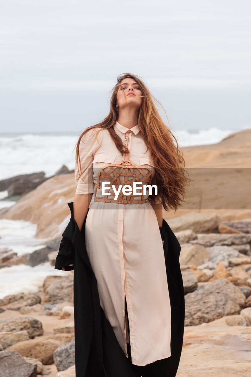 Woman with dress and harness at the beach on a windy day, portugal