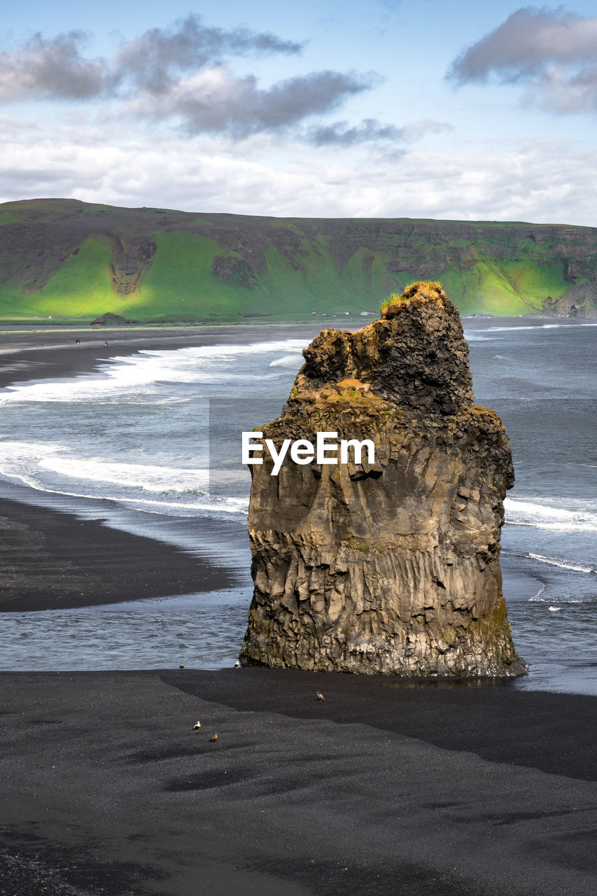 Black snad beach in vik, iceland. big solitaire rock with ocean in background.