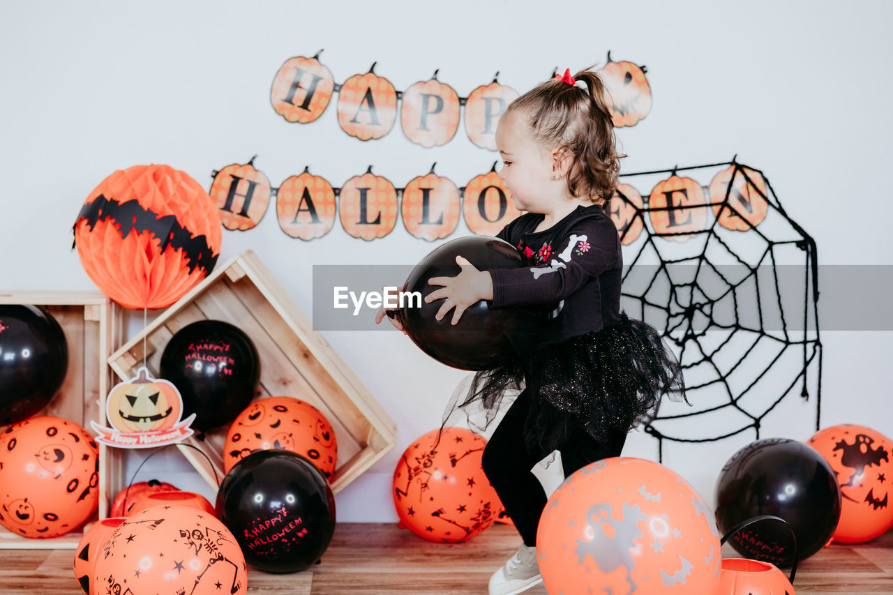 Beautiful one year old caucasian girl in halloween costume at home with halloween decoration