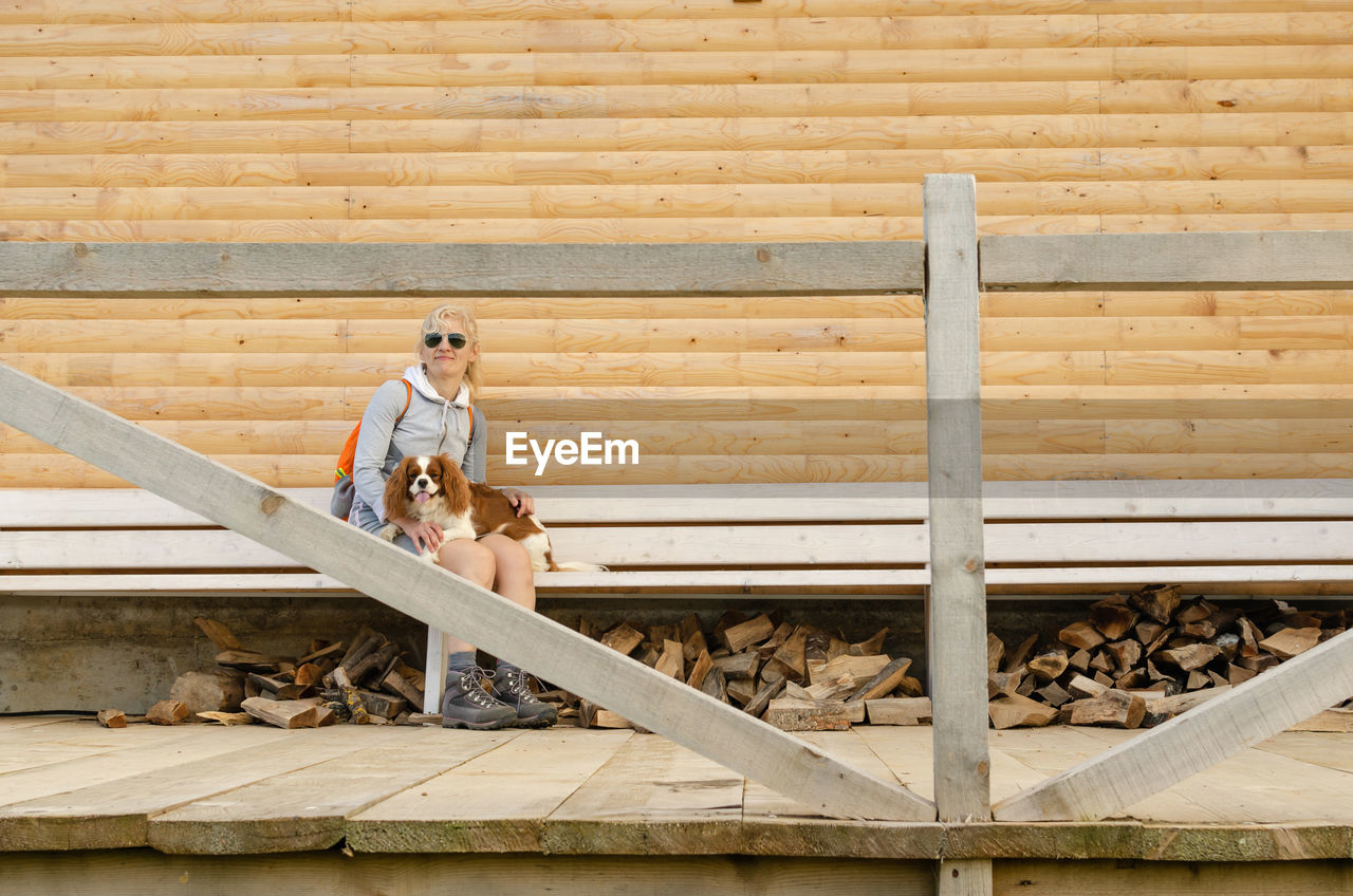 Woman sitting on a wooden bench with her dog on her lap