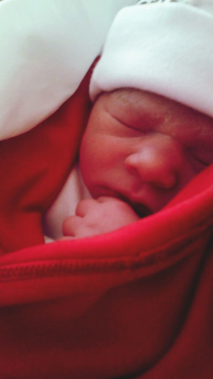 Close-up of baby girl wrapped in red blanket