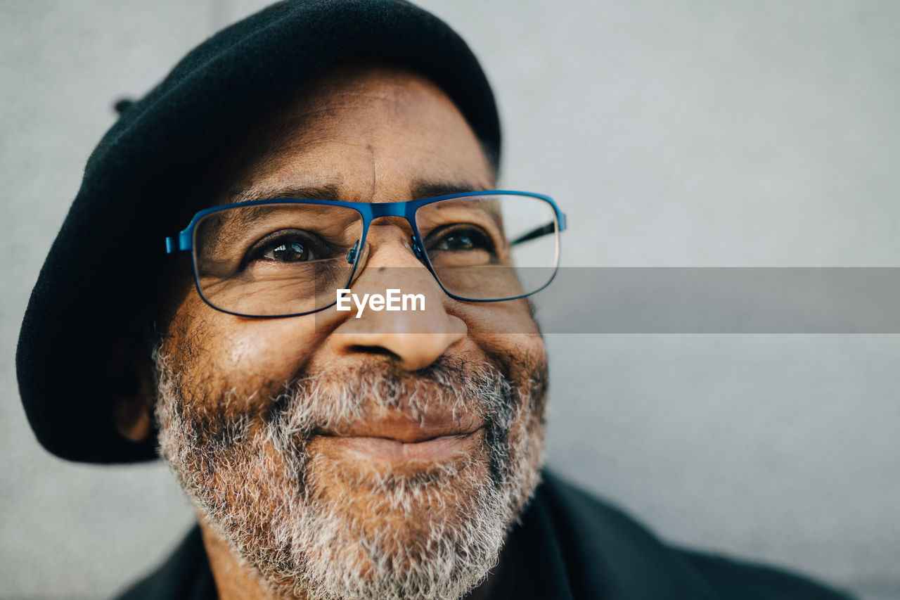 Senior man with eyeglasses looking away against wall