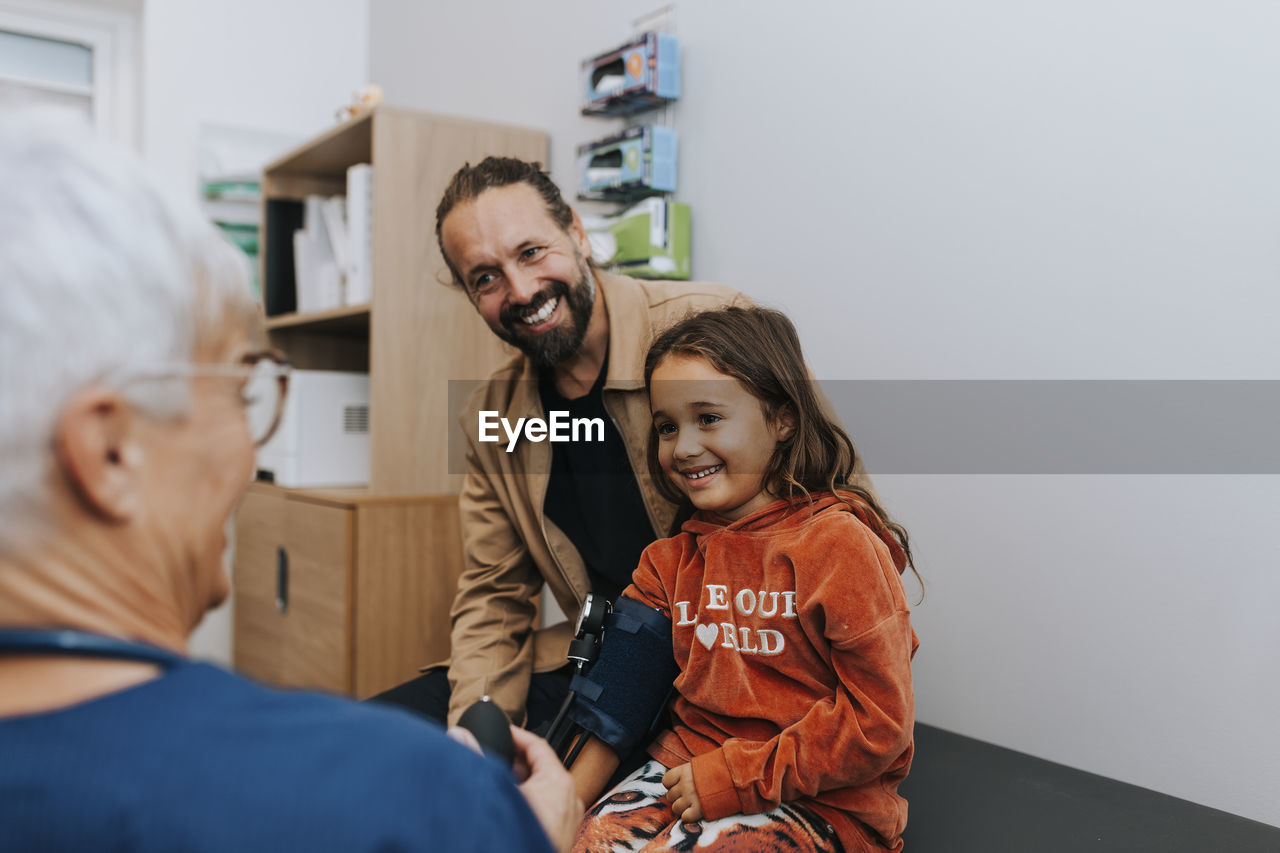 Doctor checking girls blood pressure