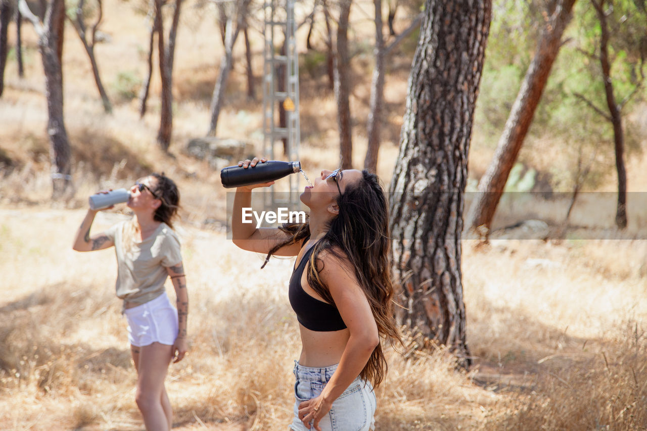Female friends drinking water at forest