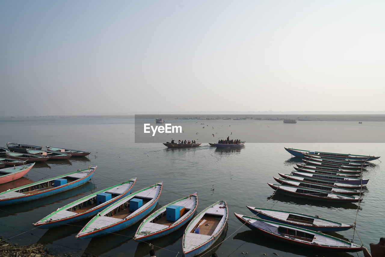 Boats moored in sea against clear sky