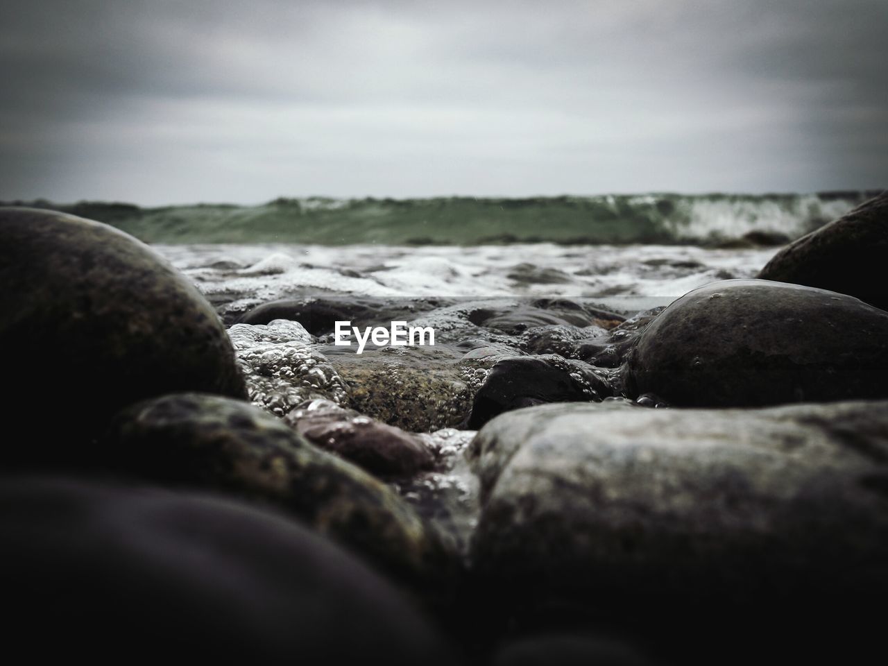 Surface level of rocks on lakeshore against sky