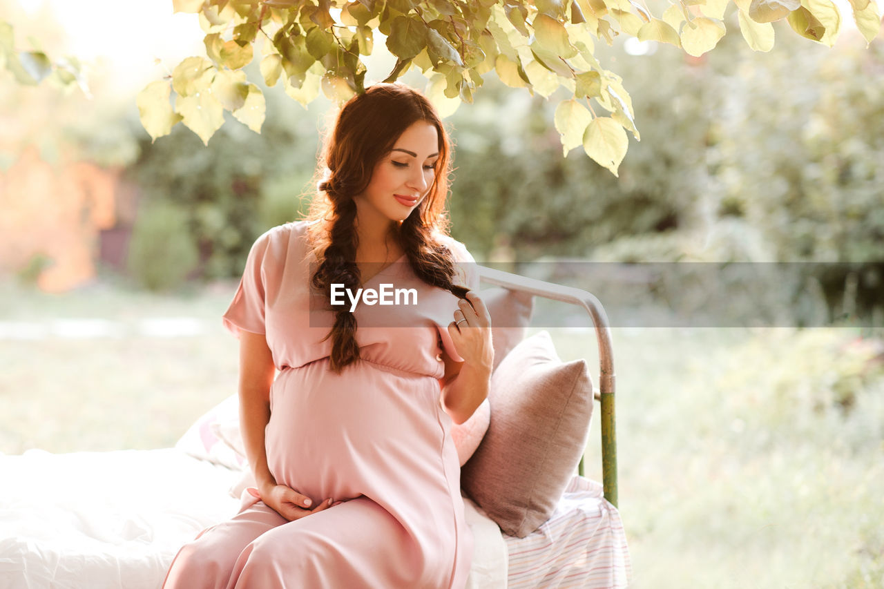 Pregnant woman sitting on bed at park