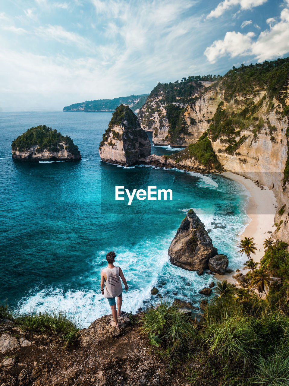 Man standing on rock at beach against sky