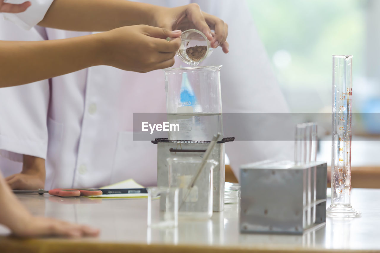 Midsection of scientists performing experiment at laboratory