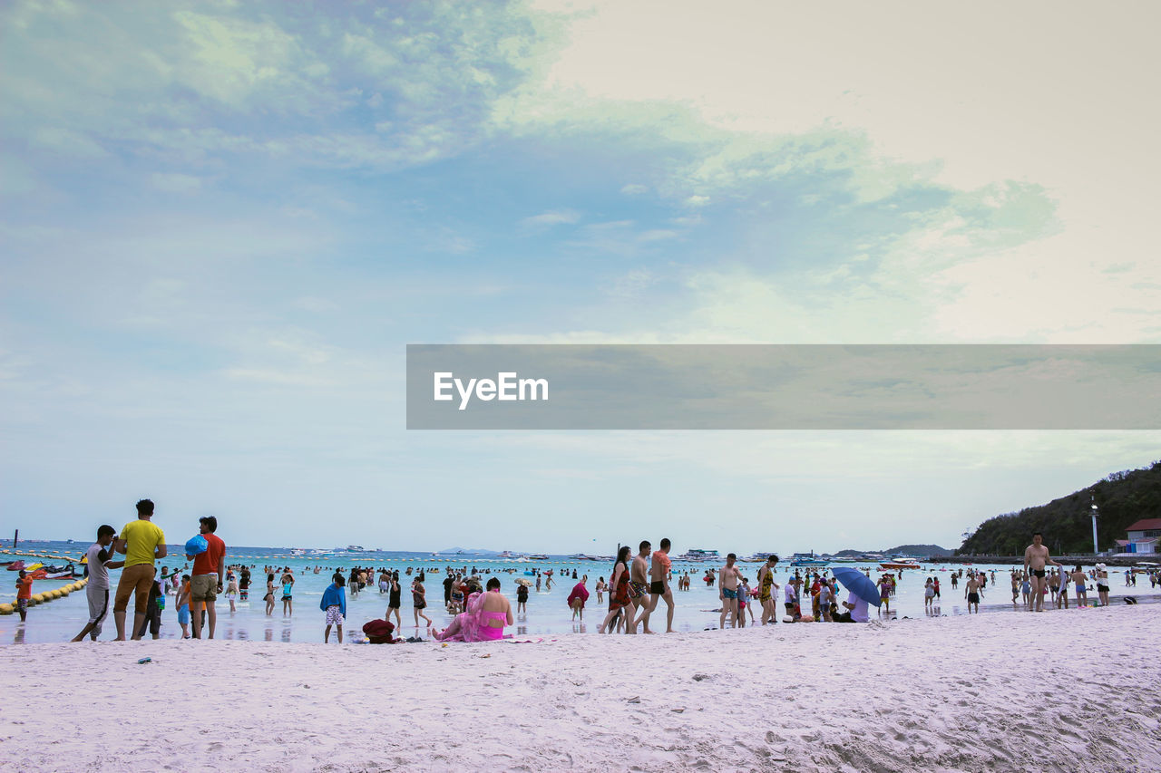 People at beach against cloudy sky