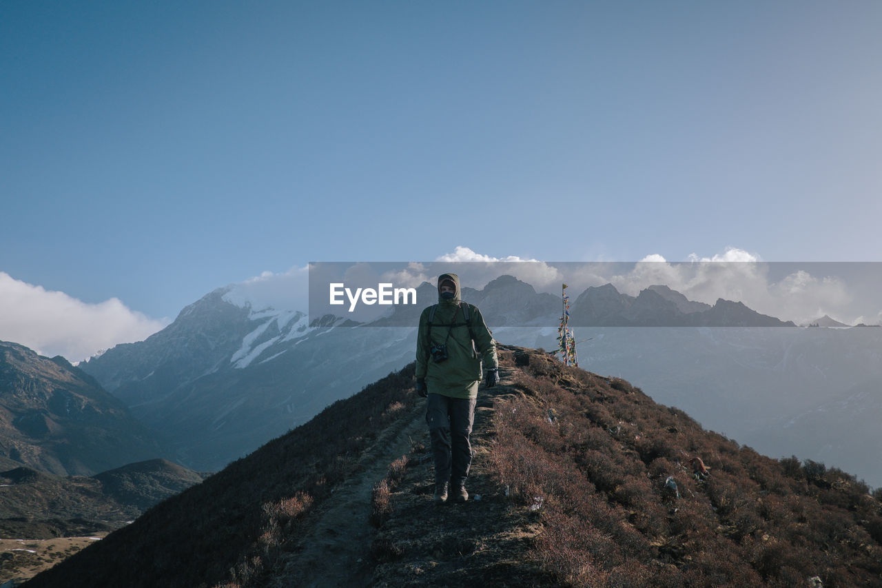 MAN STANDING ON MOUNTAIN AGAINST SKY